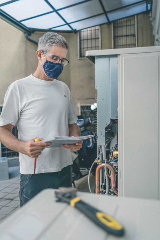 Alessandro is taking a look at notes before touching the electrical components of an HVAC outdoor unit.