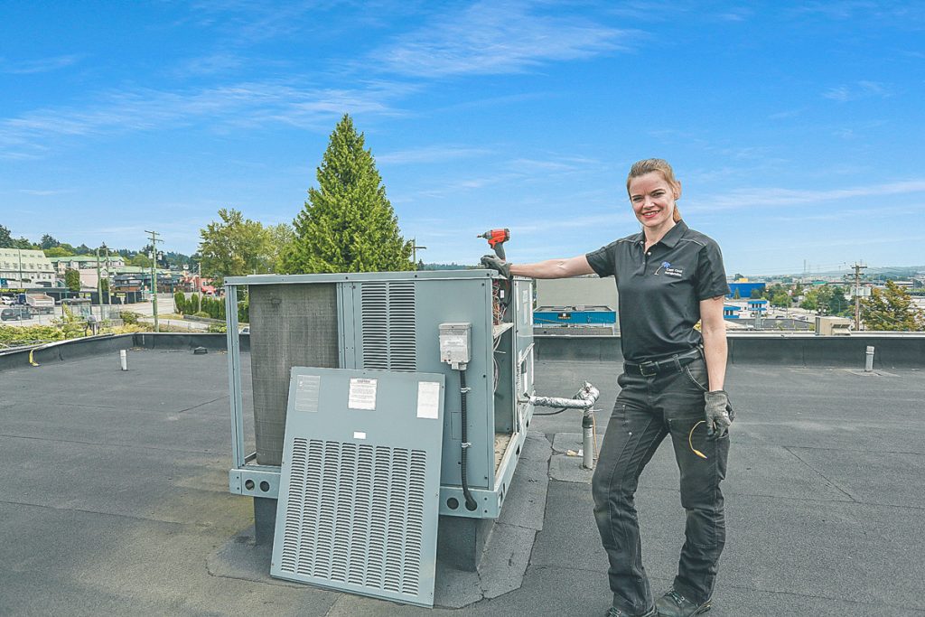 Jessica standing next to an HVAC roof unit.