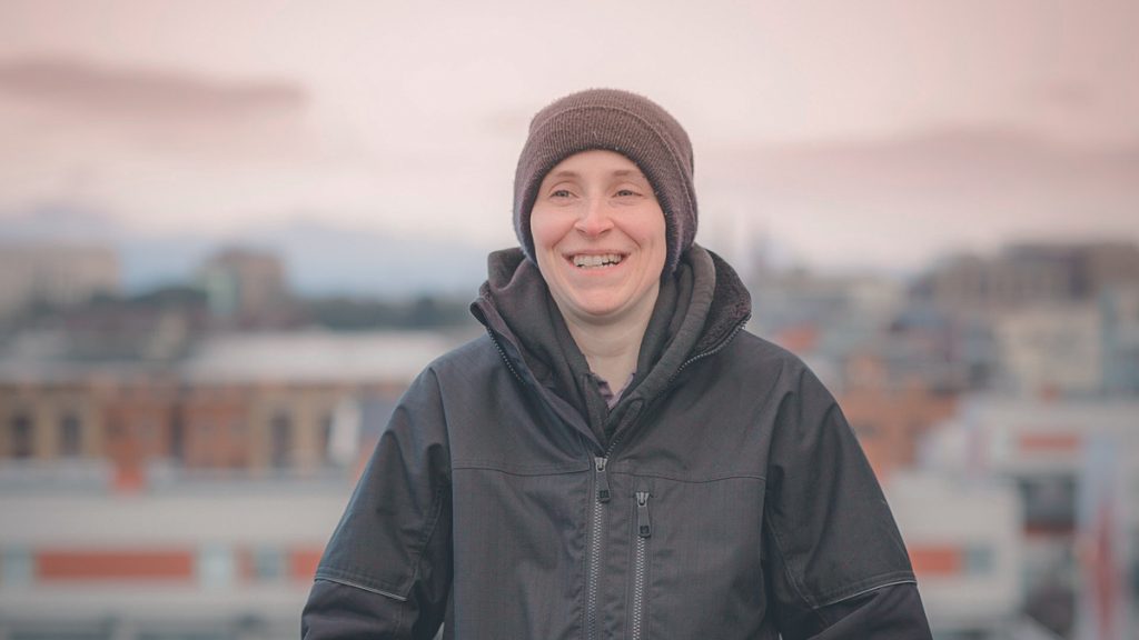 Ruth smiling on a rooftop of a building.