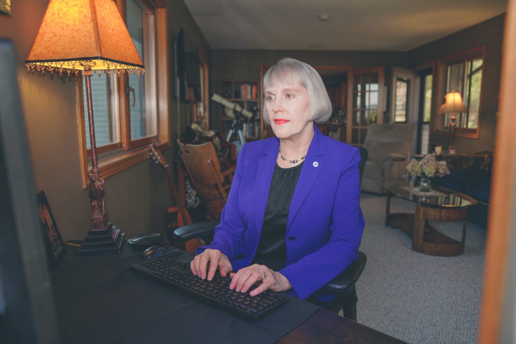 Renee is typing on a computer keyboard. She is sitting in front of her desk. 
